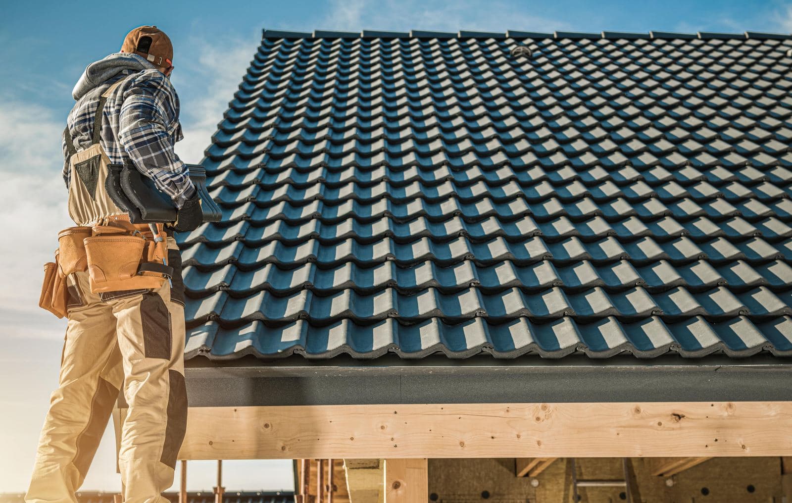 Roofer carrying tiles across a new roof deck